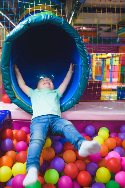 мальчик на детской площадке с цветными пластиковыми шариками. - Фото, изображение
