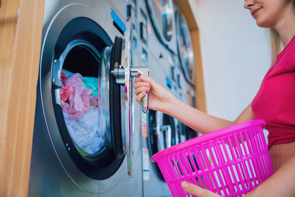 Young beautiful woman washes and dries clothes in the laundry. - Foto, Imagem