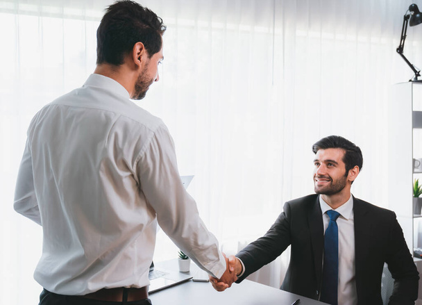 Business partnership meeting with successful trade agreement with handshake or greeting in corporate office desk. Businessman in black suit shaking hand after finalized business deal. Fervent - Photo, Image