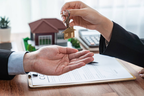 Agente imobiliário entregando a chave da casa ao comprador após o contrato bem sucedido do empréstimo da casa da assinatura. O senhorio entrega a chave da casa ao cliente. Entidade - Foto, Imagem