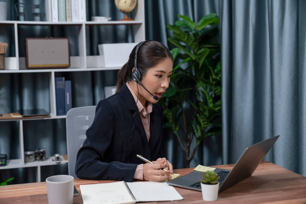 Azjatyckie call center z słuchawkami i mikrofonem pracujące na jej laptopie. Kobieta operator zapewniają wyjątkową obsługę klienta. Wspierający agent call center pomagający klientowi w dochodzeniu. Entuzjastycznie - Zdjęcie, obraz