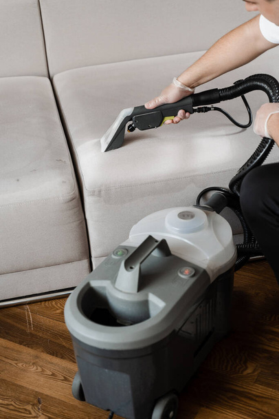 Line on couch after dry cleaning with washing vacuum cleaner extractor machine. Domestic cleaning service cleaner is removing dirt and dust from couch using dry cleaning extraction machine - Fotoğraf, Görsel