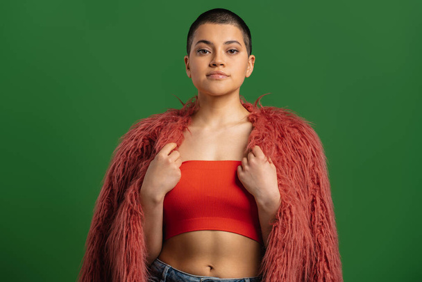 Beautiful short hair woman in fluffy jacket looking at camera against green background - Foto, immagini