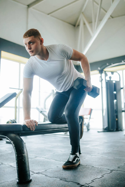 In an active gym setting, a caucasian male focuses on his physical training and lifting weights. Intense gym training session for a dedicated fitness enthusiast aiming to improve his strength - Valokuva, kuva