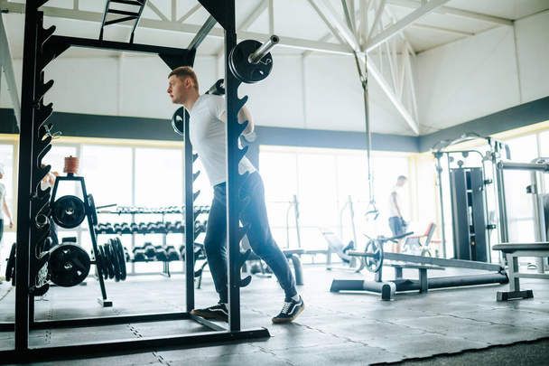 A motivated individual sweating it out in a training gym, utilizing barbells to engage in a variety of physical exercises, all aimed at improving overall fitness and strength. - Photo, image