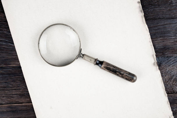 Antique vintage magnifying glass on paper background - Fotó, kép