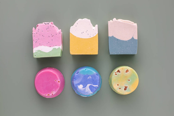 Pieces of different shapes and colors of handmade soap on a green background. The concept of natural cosmetics, hygiene. - Foto, Imagen