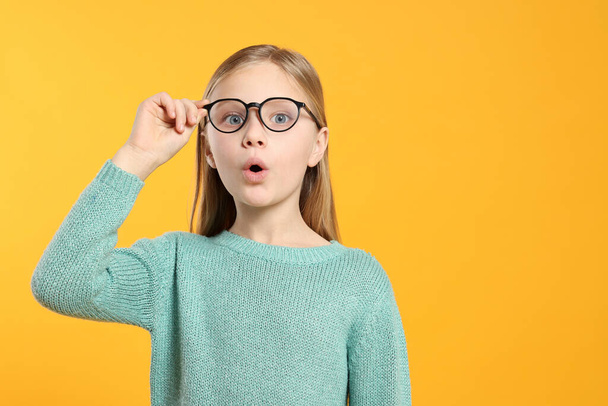 Portrait of emotional girl in glasses on orange background. Space for text - Photo, image