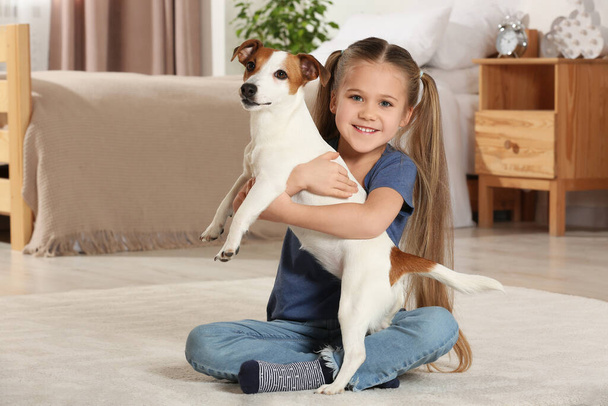 Cute girl hugging her dog on floor at home. Adorable pet - Foto, Bild