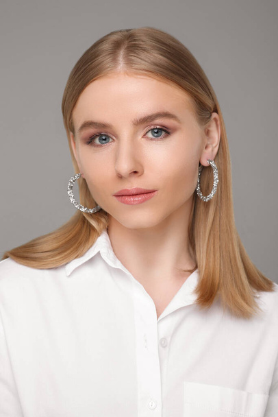 Beautiful young woman with elegant earrings on gray background - Fotografie, Obrázek