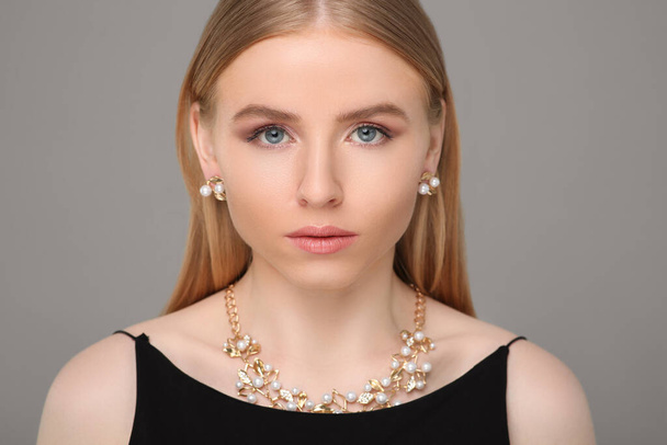 Beautiful young woman with elegant jewelry on gray background - Foto, Imagem