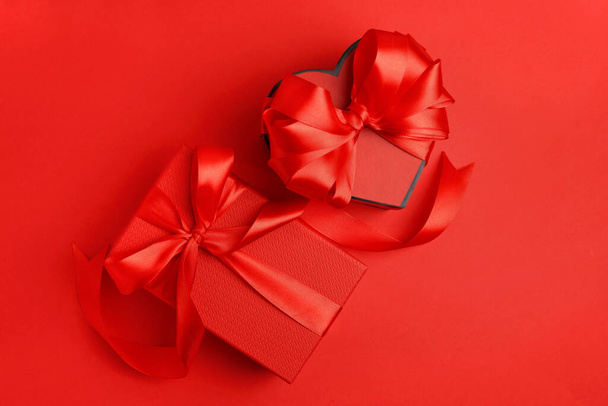 Beautiful gift boxes with bows on red background, flat lay - Foto, afbeelding