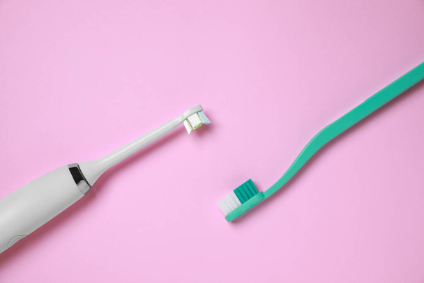 Electric and plastic toothbrushes on pink background, flat lay - Fotoğraf, Görsel