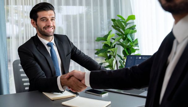 事務所のデスクで握手や挨拶で成功した貿易協定とのビジネスパートナーシップミーティング。最終的な取引の後黒のスーツ握手でビジネスマン。フェルベント - 写真・画像