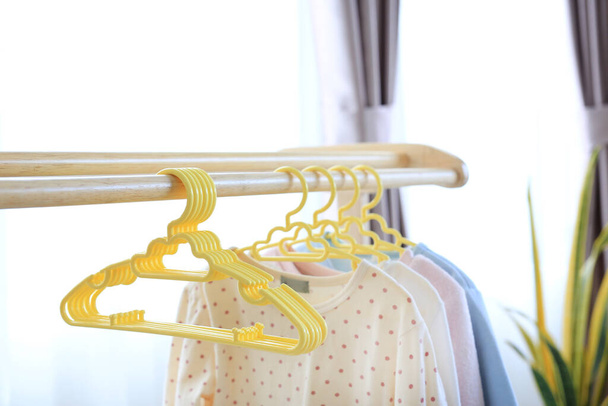 Hangers with clothes hang on a wood rack in house - Fotoğraf, Görsel