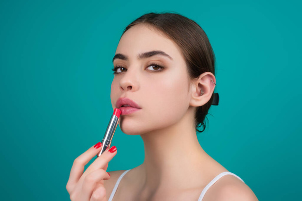 Lipstick, beauty and cosmetics. Beautiful woman applying lipstick on lips. Mockup for cosmetics, makeup. Lips color product, balm cosmetic on studio background - Fotó, kép