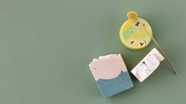 Pieces of different shapes and colors of handmade soap on a green background. The concept of natural cosmetics, hygiene. Copy space - Foto, afbeelding