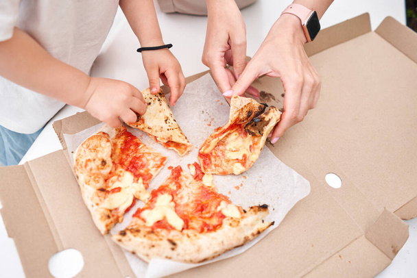 Pizza delivery concept. Baking in a cardboard box on a wooden background. Baked a delicious pizza Margarita in a traditional wood-burning oven in a Neapolitan restaurant, Italy. High quality photo - 写真・画像