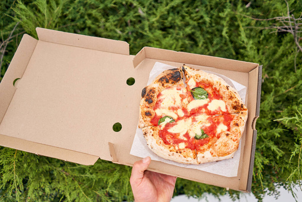 Pizzalähetyskonsepti. Leivonta pahvilaatikossa puupohjalla. Paistettu herkullinen pizza Margarita perinteisessä puuuunissa napolilaisessa ravintolassa Italiassa. Laadukas kuva - Valokuva, kuva
