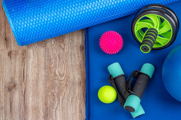 Sportuitrusting voor fitness en yoga. Minibellen, body shaping roller, spiky en gladde ballen voor acupunctuur punten op het lichaam, roller voor het trainen van de pers en terug op een yoga mat. Kopieerruimte. - Foto, afbeelding