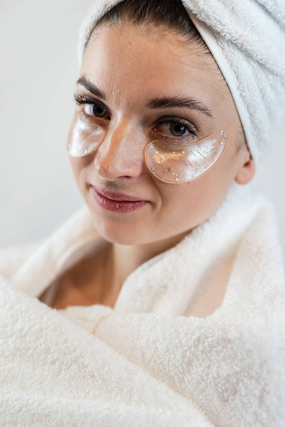 Mujer caucásica en toalla blanca con parche de colágeno en la cara, cuidado de la piel. Cosmética natural para el cuidado de la belleza. Concepto tratamientos de belleza - Foto, imagen