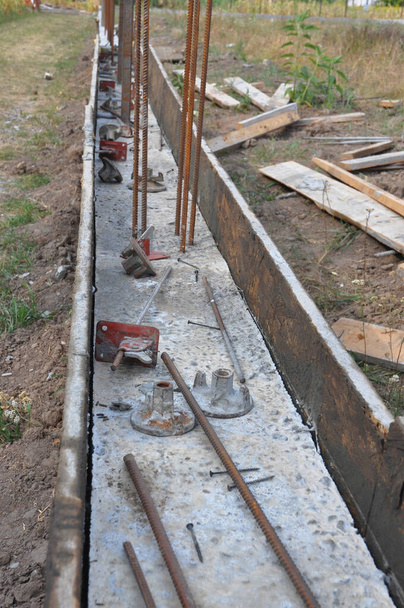 Бетонний підвал встановлюється вздовж довжини цього паркану. Налити бетонні опори в дерев'яні плити арматурними брусками для нового огорожі будинку
. - Фото, зображення