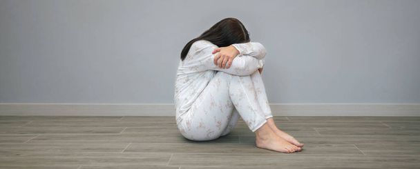 Felismerhetetlen nő mentális zavarokkal és öngyilkossági gondolatokkal a padlón ülve. - Fotó, kép