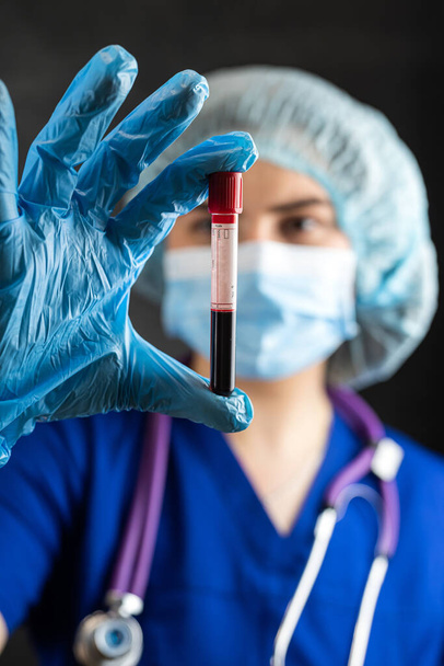 Mujer bonita joven médico mira en el tubo de ensayo con muestra de sangre, covid19. Investigación médica, coronavirus - Foto, Imagen