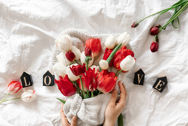 Bouquet of fresh tulips and decorative word Love in a white bed, top view. - Photo, Image