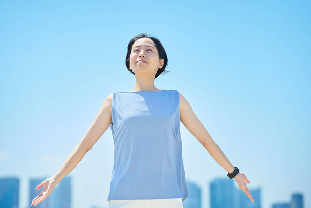 Een vrouw met een ontspannen uitdrukking onder de blauwe hemel - Foto, afbeelding