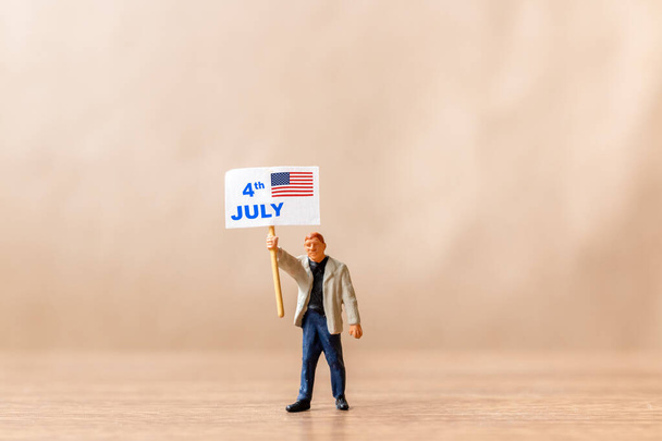 Pessoas em miniatura, americanos a levantar bandeiras em comemoração ao 4 de Julho e ao Dia da Independência - Foto, Imagem