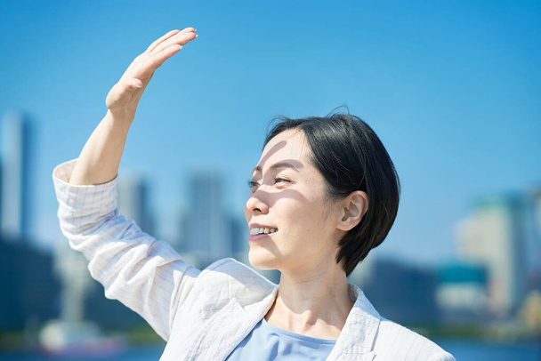 Жінка блокує сильне сонячне світло рукою в прекрасний день
 - Фото, зображення