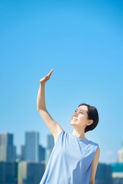 Uma mulher bloqueando a forte luz solar sob o céu azul no belo dia - Foto, Imagem