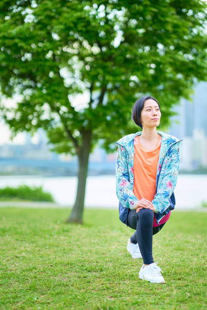 Mujer asiática haciendo ejercicio en el espacio verde urbano - Foto, imagen