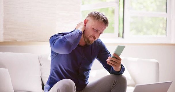 Man With Neck Pain Sitting Using Mobile Phone - Foto, Imagen