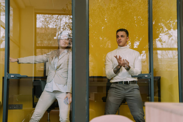 Zwei Geschäftskollegen beim Abschied in der Telefonzelle im Büro - Foto, Bild
