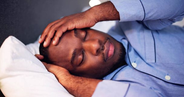 Jeune homme africain souffrant de fièvre allongée sur le lit
 - Photo, image