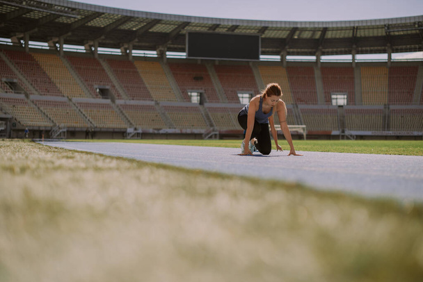 Two beautiful female friends are about to check who is faster. Running on a sports track at the stadium - Photo, Image