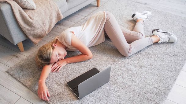Home nap. Online fatigue. Digital detox. Tired exhausted lady lying on floor with laptop falling asleep watching internet content in domestic interior free space. - 写真・画像