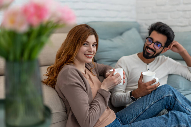 Romantic couple drinking coffeee at home relaxing in cosy living room. - Fotó, kép