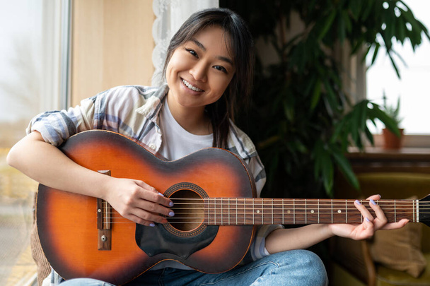 Girl with guitar. Cute young asian girl with guitar at home - Photo, image