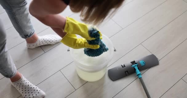 Lastik eldivenli bir kadın kovada bez sıkar ve yerleri siler. Temizlik ve temizlik hizmetleri - Video, Çekim