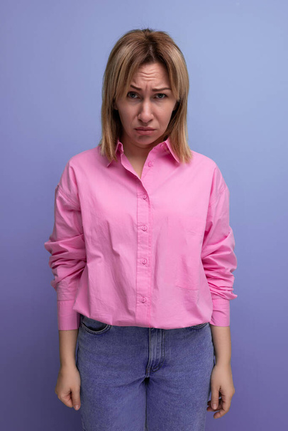 joven mujer rubia confiada vestida con una camisa rosa de moda para la oficina resuelve problemas de trabajo por teléfono. - Foto, imagen