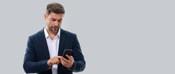 Man in suit using mobile phone isolated on studio background. Portrait of confidence middle aged millennial man using cellphone. Guy with smartphone isolated studio background. Banner, copy space - Φωτογραφία, εικόνα