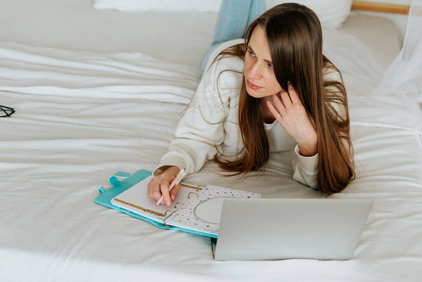 Distance learning online education and work. Business woman writes to do list in notebook. Cropped freelance girl with laptop at home office. Using computer and online shops. Copy space blank mockup. - Φωτογραφία, εικόνα