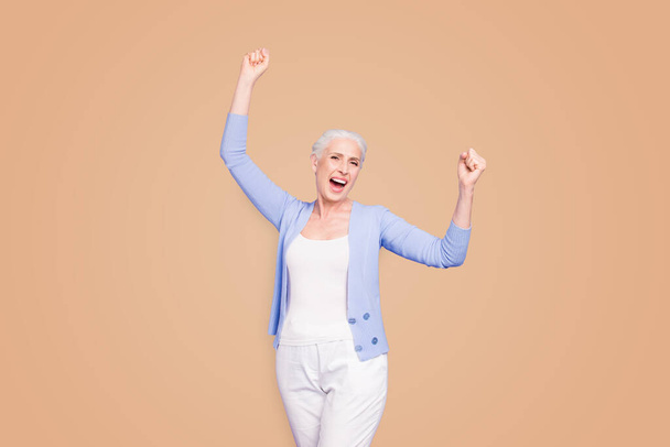Grey haired old happy woman wearing casual, raising hands up, celebrating party winning, opened mouth. Isolated over violet purple background. - Foto, Imagen