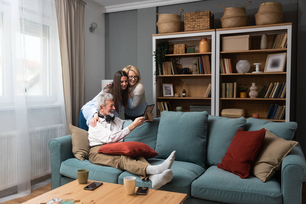 Happy three-generation family hugging sit indoors enjoy time together at home, laughing grown up daughter with 70s dad and middle-aged 50s mom warm relations, intergenerational relative people concept - Fotoğraf, Görsel