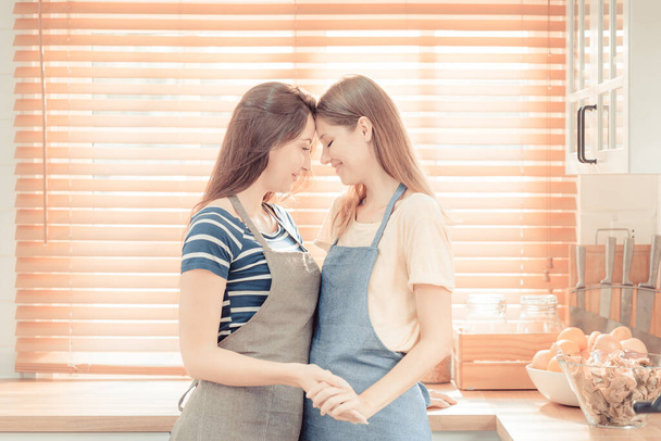 Lesbian Couple Together Indoors Concept. Lesbian in the kitchen. Young women are in a mutual lesbian love relationship. LGBT concept. warm tone. - Photo, Image
