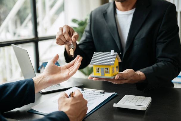 Real estate broker agent presenting and consult to customer to decision making sign insurance form agreement, home model, concerning mortgage loan offer in office - 写真・画像