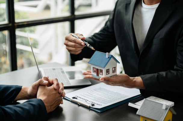 Real estate broker agent presenting and consult to customer to decision making sign insurance form agreement, houses models, concerning mortgage loan offer in office - 写真・画像